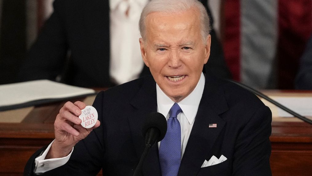 President Joe Biden holds up a Laken Riley button as he delivers the State of the Union address to a joint session of Congress at the U.S. Capitol, Thursday March 7, 2024, in Washington. (AP Photo/Andrew Harnik)